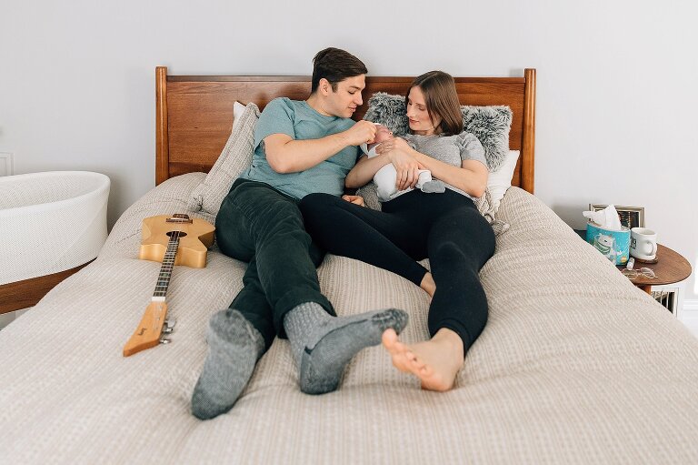 Mom and Dad on bed with newborn. 
