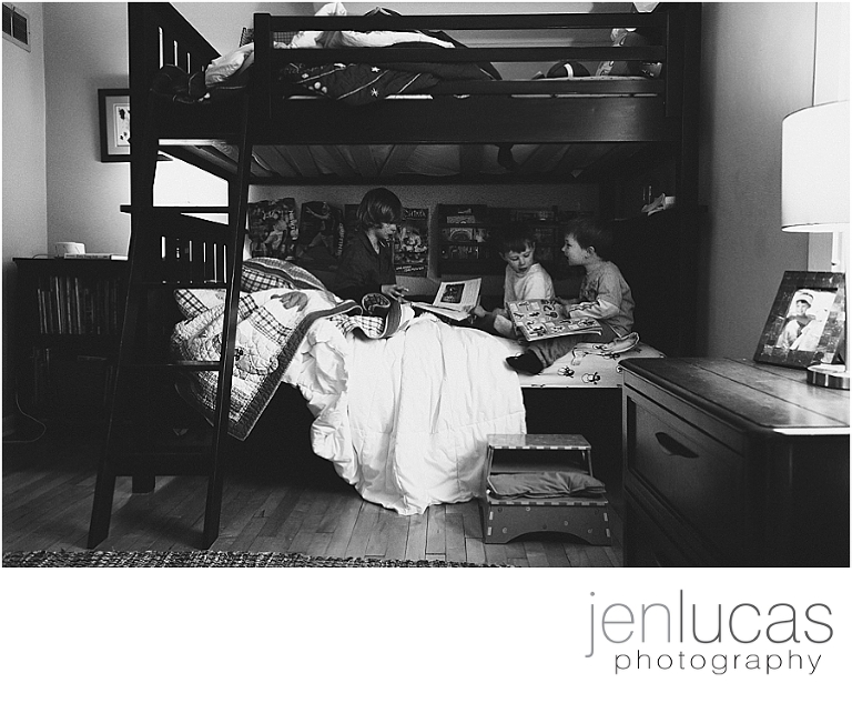 Black and white. Three boys sit in a bunk bed together 