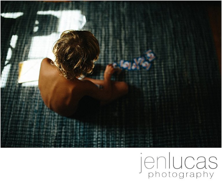 Top down view of a young boy lining up Pokemon cards on a blue rug. 