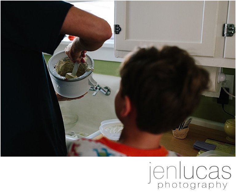 A small boy watches his father take ice cream out of a homemade container. 
