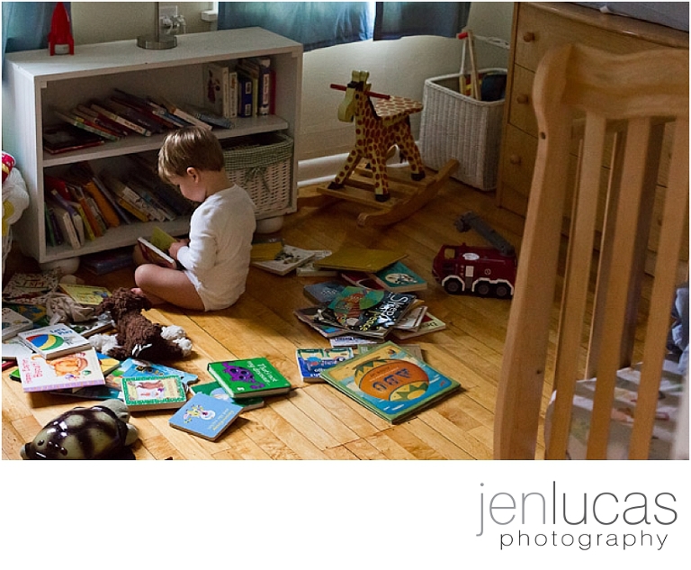 Young boy sits in a circle of his book on his bedroom floor