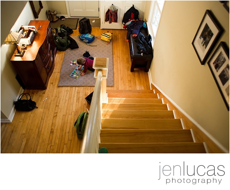 Top down view from the stairs of a young boy playing a puzzle in the middle of the foyer floor. 