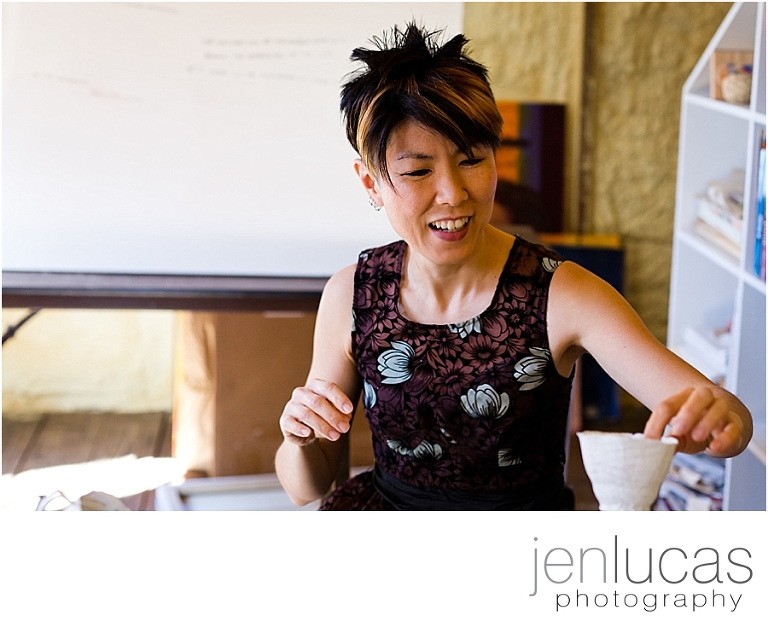 portrait of Soyoung Kim as she picks up a paper teacup that she made. 