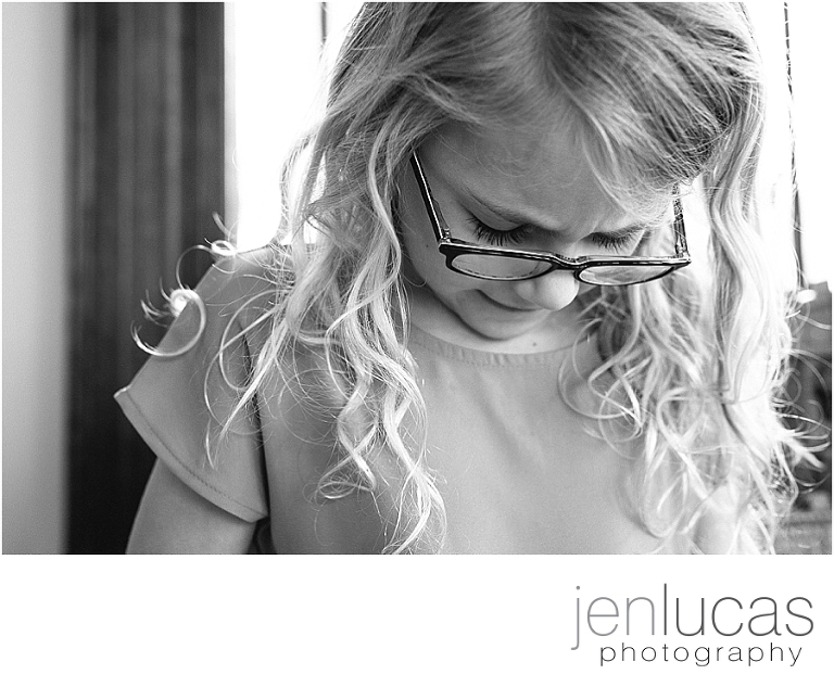 Black and white environmental portrait of first grade girl wearing glasses. 