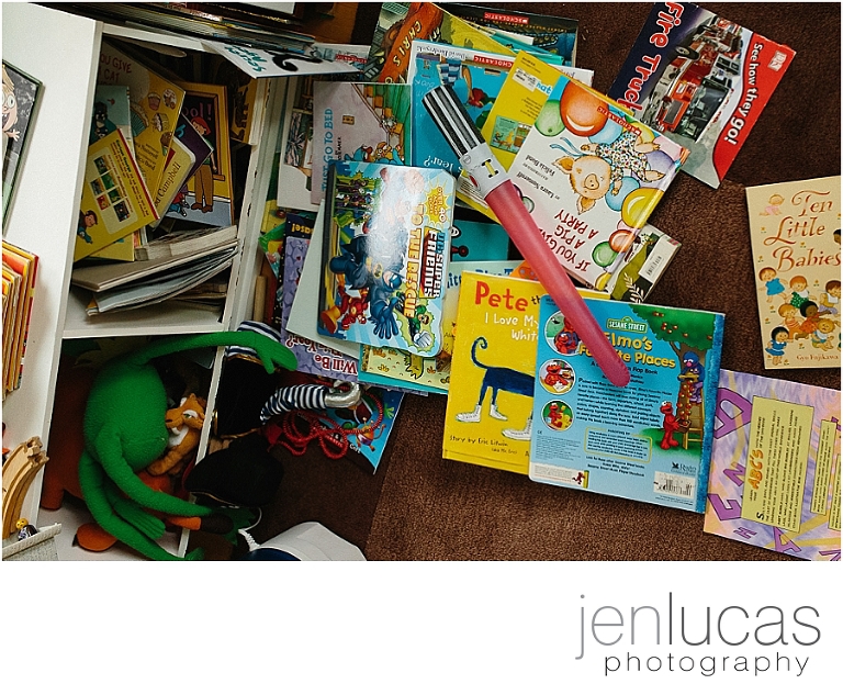 Scene of dozens of children's books scattered all over the floor. A toy light saber lies on top. 