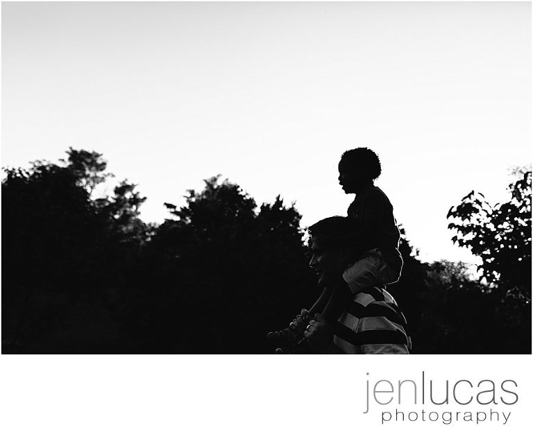 black adn white silhouette of dad holding son on his shoulders in the arboretum. 