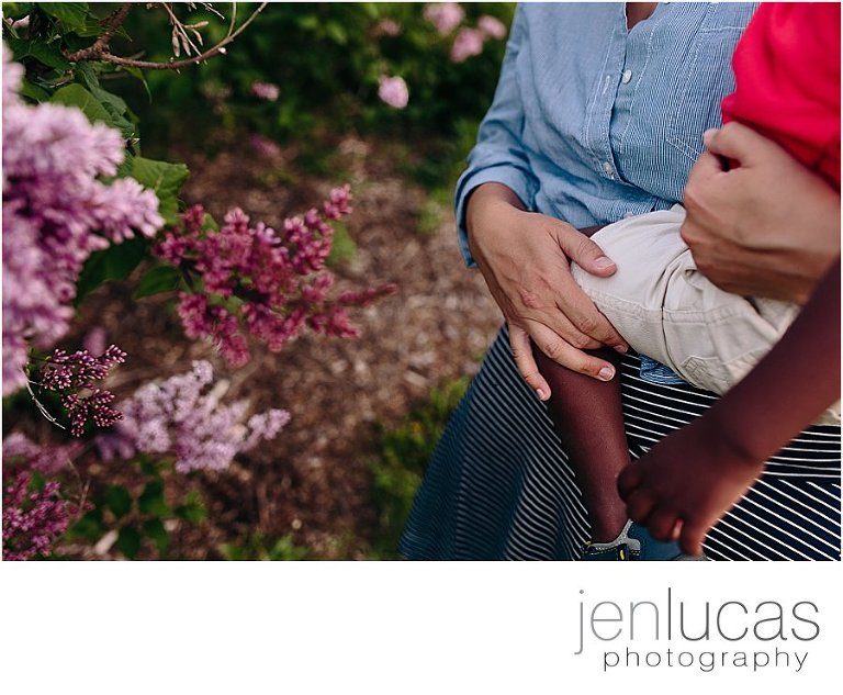 Mom holds son near the blooming lilacs.