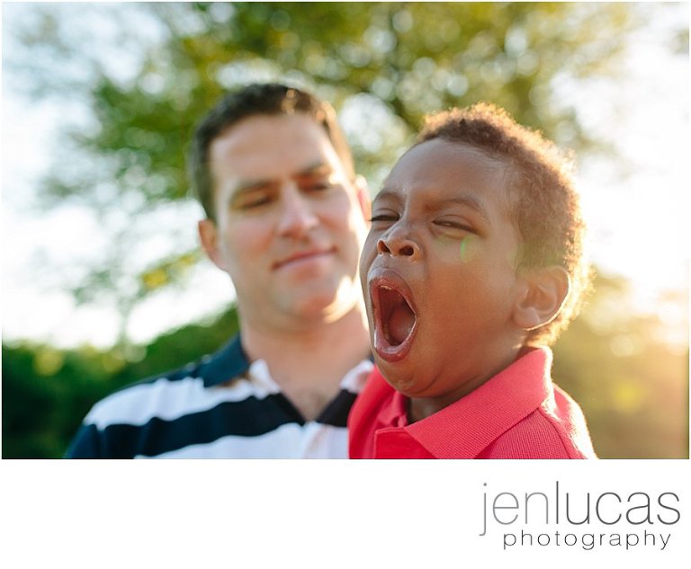 Boy yawns as his dad holds him. 