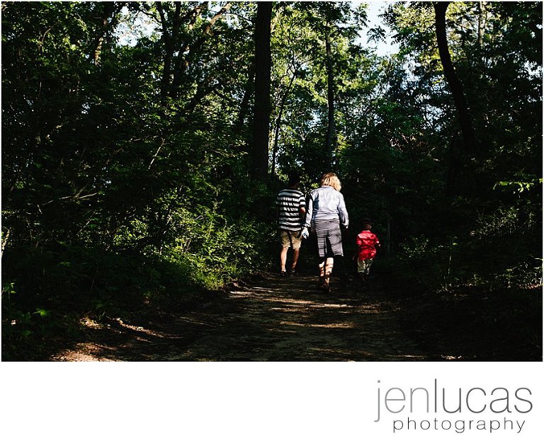 Family of 3 walk into the woods--right into a pocket of light. 