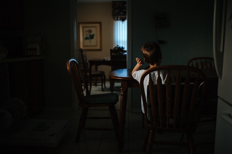 Young boy sitting at the kitchen table alone at grandparents house.