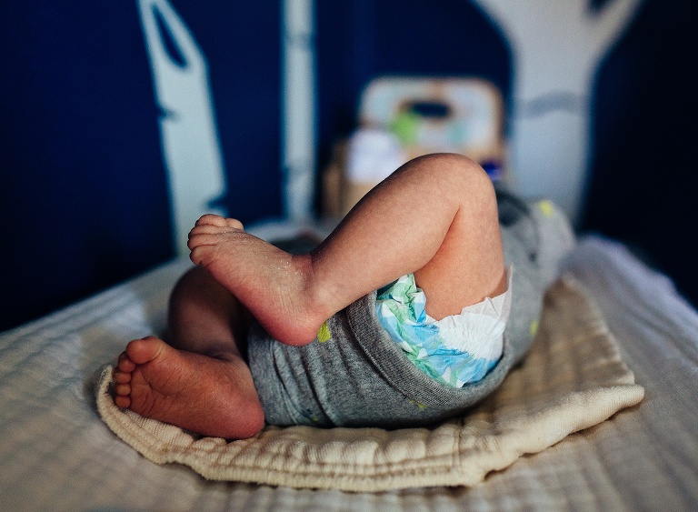 Newborn baby lays down on changing table