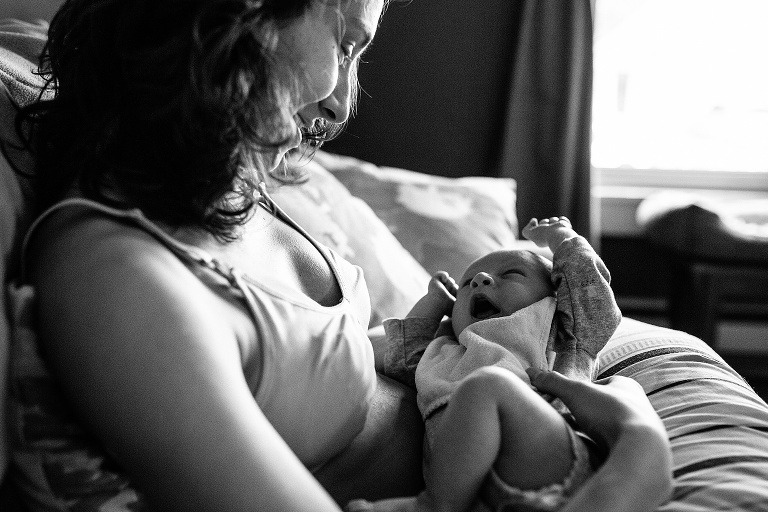 Black and white. Mother smiles while holds newborn baby in her arms