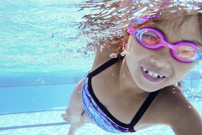 Underwater image of young girl swimming in the pool.