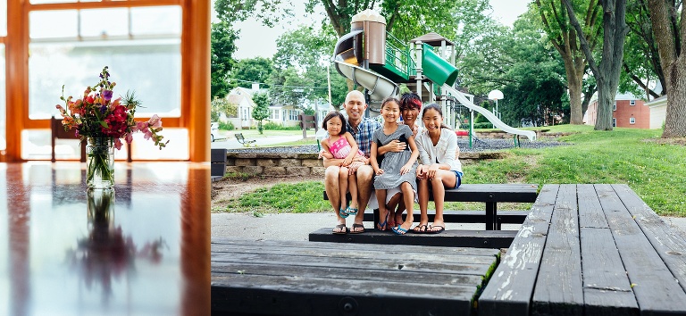 Family of five sit on a bench at a neighborhood park.