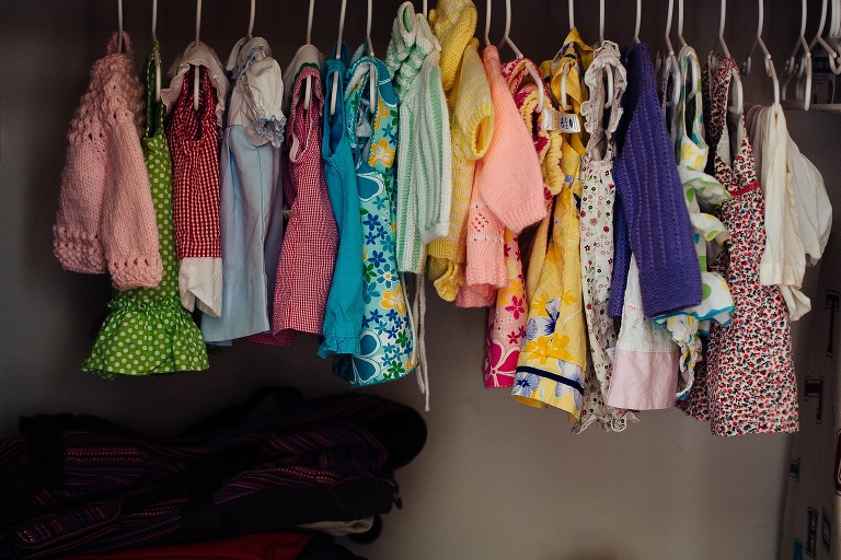 Row of baby girl cloths hanging up in a closet.