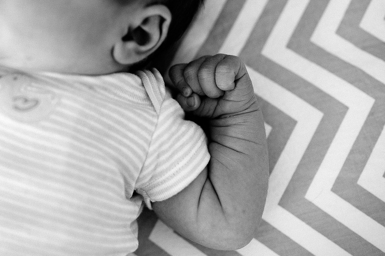Black and white. Sleeping newborn baby's arm. hand curled up near her face.