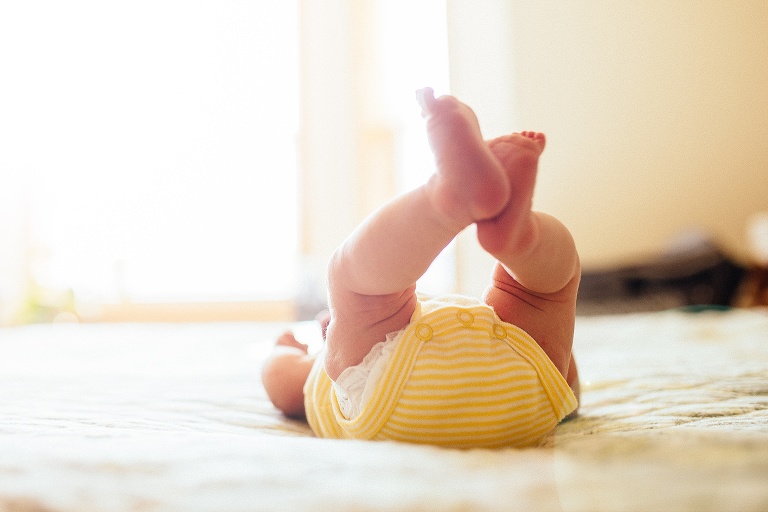 Sleeping newborn baby lays with her feet up in the air.