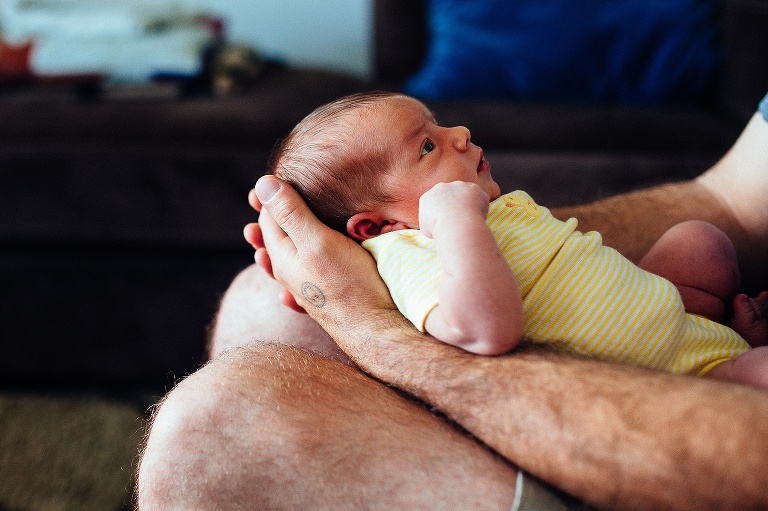 Father holds his newborn baby girl on his lap.