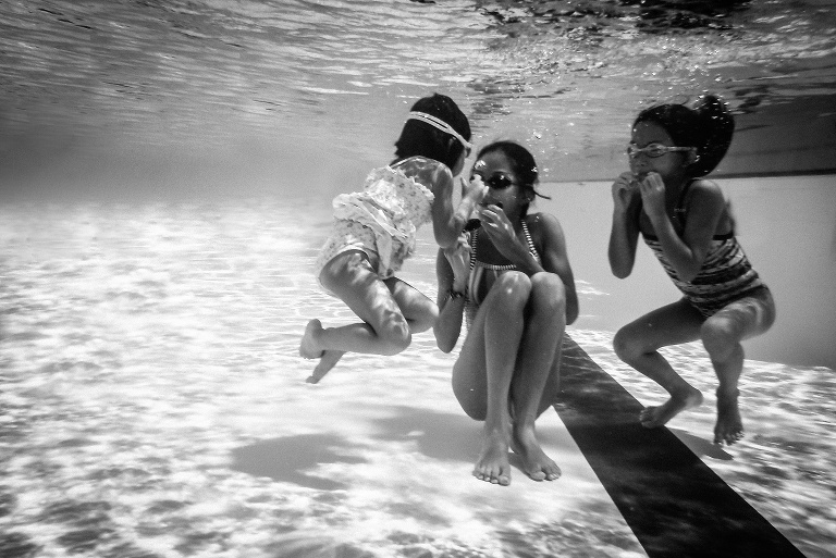 Black and white. Underwater image of three sisters all swimming.
