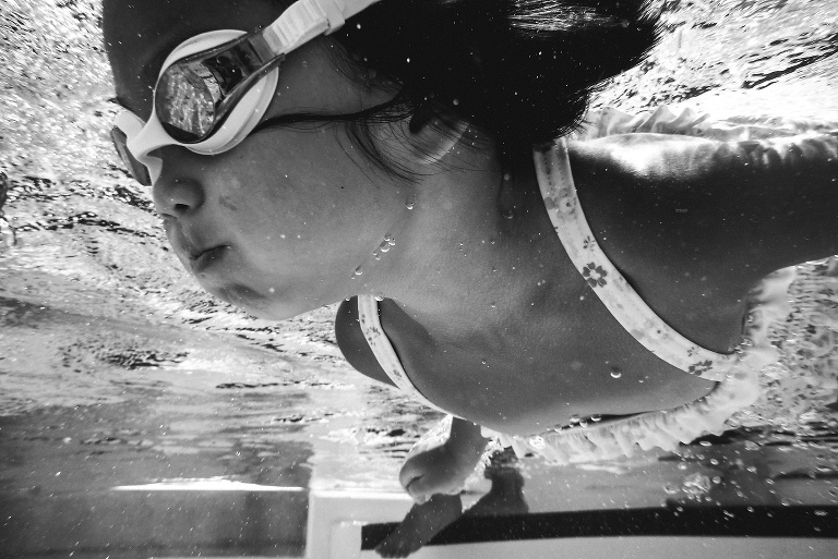 Black and white. Underwater image of young girl swimming in the pool.
