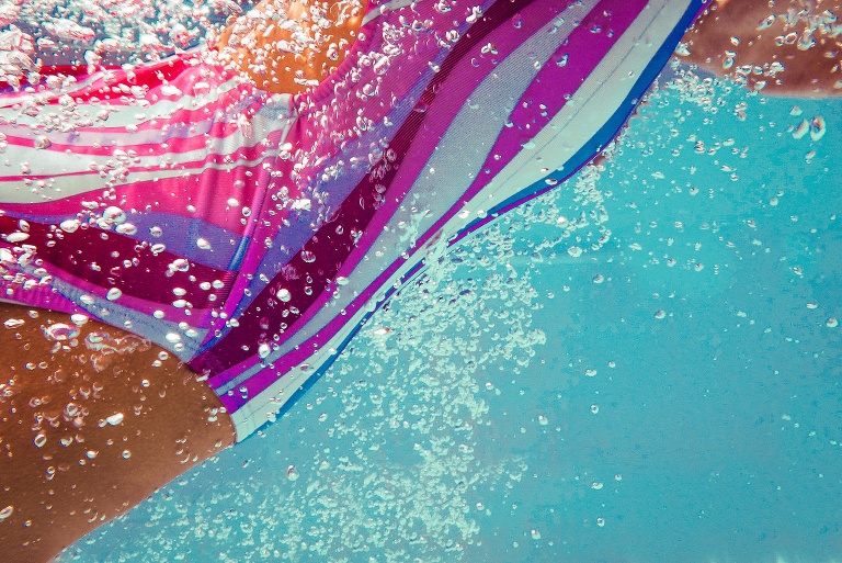 Underwater image of rainbow swimsuit with bubbles all around.