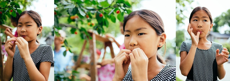 Girl standing outside eating cherries fresh of the tree.