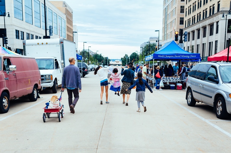 Family of five walk down the street during a farmers market.