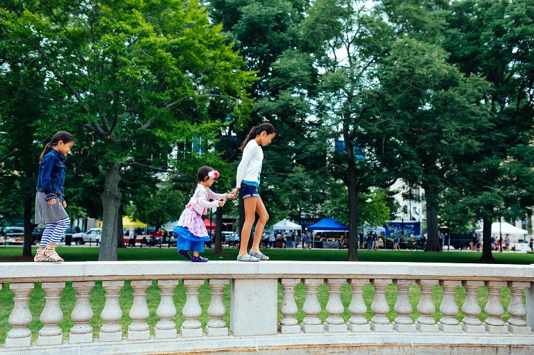 The sisters walk across a ledge downtown by the farmers market.