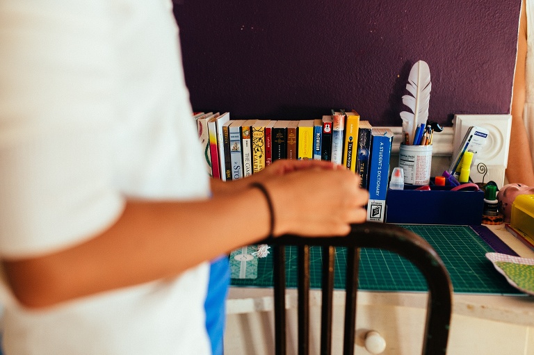 Girl standing next to desk with a craft mat and books.