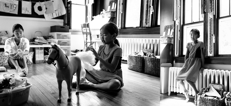 Black and white. Three sisters play in the playroom together.