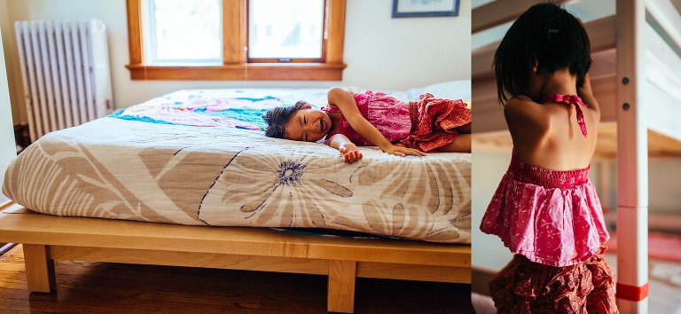Young girl laughs while laying on a bed.