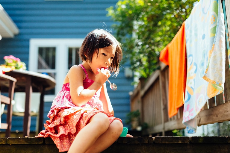Young girl sitting on back patio eating a snack.