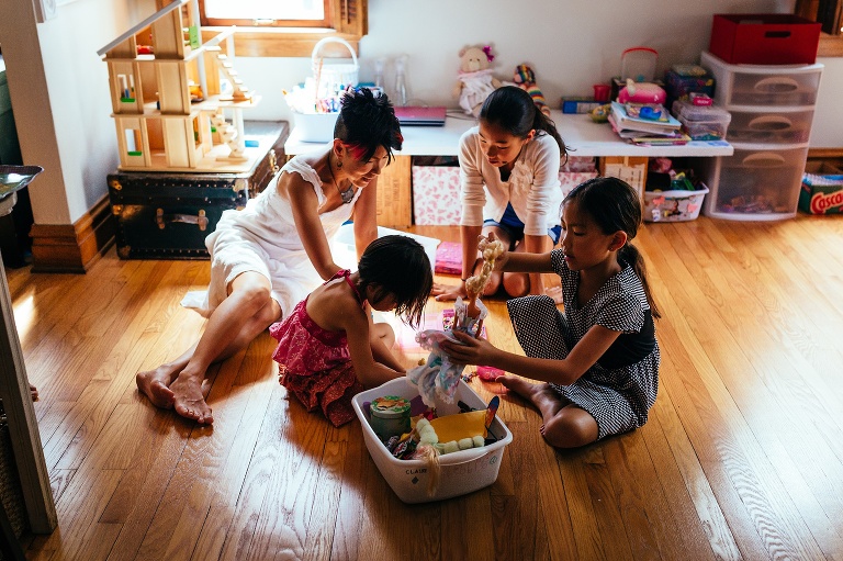 Mom sits on the floor playing with her three daughters.