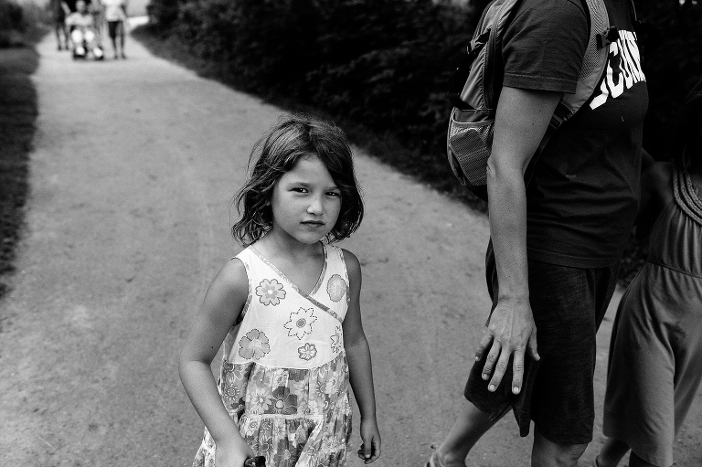 Black and white. Family walking down a path. Mother holds hand out for daughter.