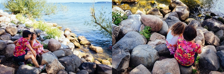 Two girls sitting on rocks next to a lake.