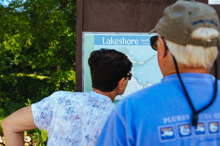 Woman stands looking at a map posted outside on a sign.
