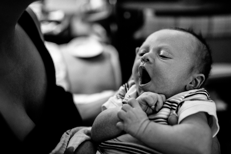 Black and white. Mom holds yawning newborn baby.