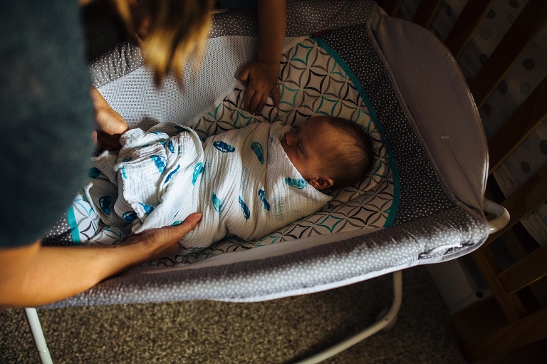 Sleeping newborn baby lays down in baby bed.