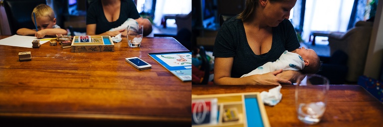 Mother sitting at a table holding newborn baby. Young boy sitting next to her stamping a piece of paper.