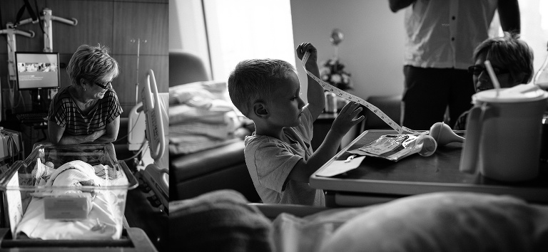 Black and white. Family sitting around in the hospital room after newborn baby was born.
