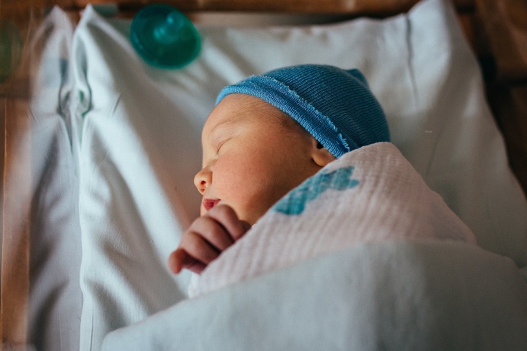 Newborn baby sleeps in the hospital bassinet.