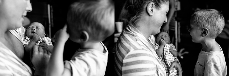 Black and white. Mom holds out newborn baby showing him to his brother.