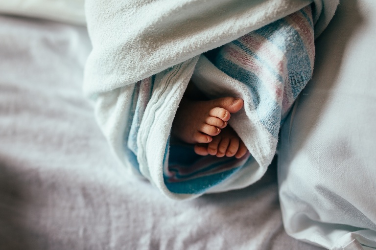 Newborn baby's tiny feet in hospital blanket.