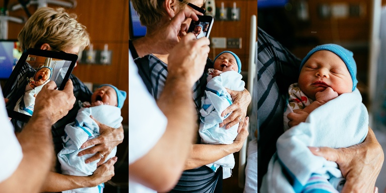 Grandma holds newborn baby as father takes a picture of them.