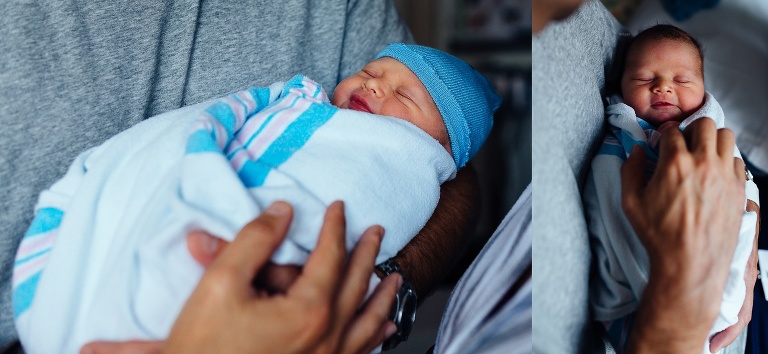 Swaddled newborn baby sleeping in fathers arms.