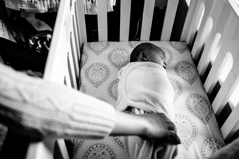 Black and white. Swaddled newborn baby sleeps in crib.
