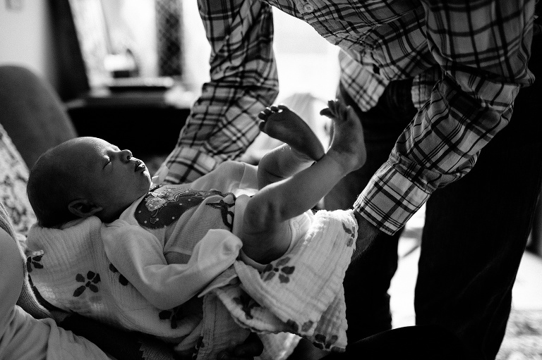 Black and white. Father picks up sleeping newborn baby girl.