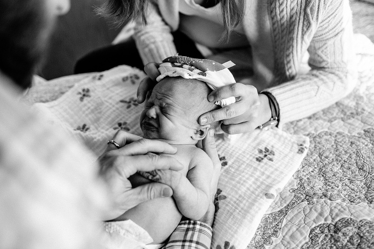 Black and white. Mother and father dress newborn baby.