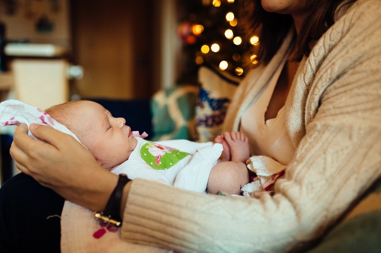 Mother holds sleeping newborn baby on her lap.