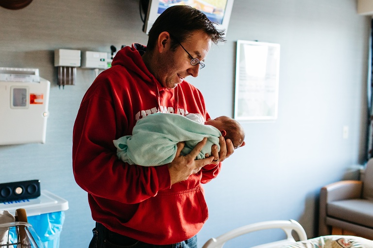Father holds newborn baby in the hospital.